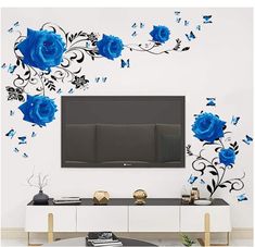 a living room with blue flowers and butterflies on the wall, in front of a flat screen tv