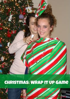 two women standing in front of a christmas tree with the words christmas wrap it up game