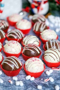 there are many chocolates with white and red frosting on the table next to candy canes