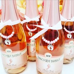 several bottles of wine with pink ribbon around the neck and necklaces on each bottle