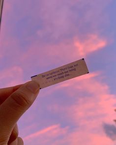 a person holding up a piece of paper with the sky in the background