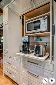 a microwave and toaster combination in a kitchen with white cabinets, wood floors and hardwood flooring