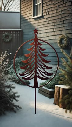 a metal christmas tree on top of a pole in the snow next to a house