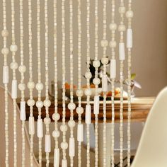 a table with a white chair and some beads hanging from it