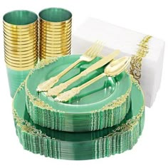 a green plate with gold rimmed forks and napkins next to stacks of gold plates