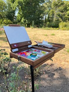 an easel sitting on top of a wooden table in the middle of a field