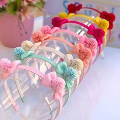 four headbands with bows and pom - poms on them sitting next to a potted plant