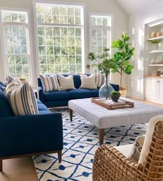 a living room filled with blue couches and pillows on top of a white rug