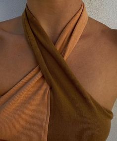 a close up of a woman wearing an orange top with a tie around her neck