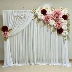 the backdrop is decorated with white and pink flowers, gold leaves and red velvet roses