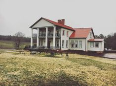 a large white house sitting on top of a lush green field