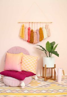 a bedroom with pink walls and colorful pillows on the bed, along with hanging tassels