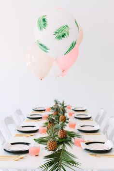 the table is set with pineapples and balloons