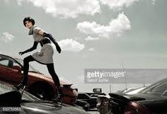 a woman standing on top of a car in the middle of a parking lot next to other cars