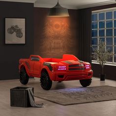 a red truck is parked in a room with a large window and rug on the floor