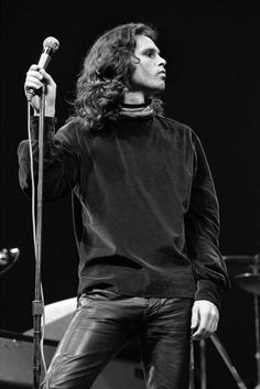 a man with long hair holding a microphone in his right hand and looking off to the side