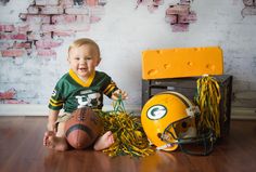 a young boy sitting on the floor with a football and helmet in front of him