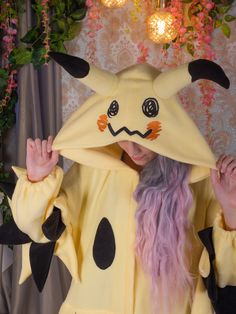 a woman in a pikachu costume is covering her face with the hood up