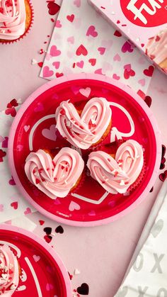 cupcakes with frosting in the shape of hearts on a pink plate next to valentine's day boxes