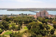 an aerial view of a golf course, water and buildings in the distance with trees on either side