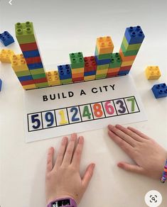 two hands are next to a sign with legos on it that says build a city