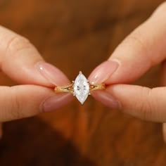 a woman's hands holding an engagement ring with a pear shaped diamond on it