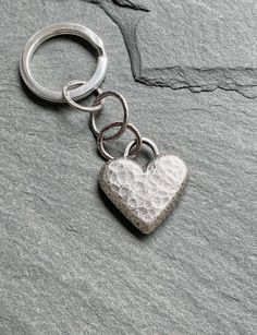 a silver heart shaped keychain sitting on top of a rock