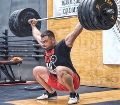 a man is squatting down with a barbell in his hand and lifting the barbell