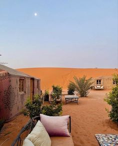 an outdoor seating area in the middle of a desert with trees and bushes around it