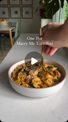 a person is cutting into a bowl of pasta with meat and spinach in it