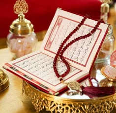 an open book on a table with beads and other items around it in a bowl