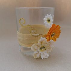 there is a glass with some flowers in it and the letter s on top of it