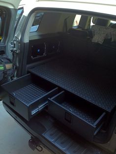 the back end of a white van with two drawers in it's cargo area