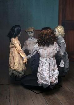 three dolls are standing next to each other on a wooden floor in front of a door