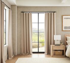 a bed room with a neatly made bed and a large window that has curtains on it