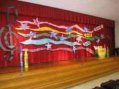 the stage is decorated with colorful paper streamers and music notes on red drapes