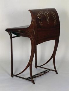 a wooden desk with an intricate design on the top and bottom shelf, sitting against a white background