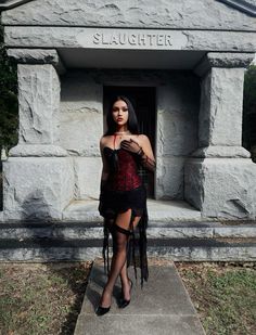 a woman standing in front of a stone monument with her hands on her hips and wearing black stockings