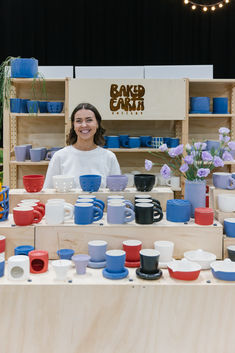 a woman standing behind a table filled with cups and bowls