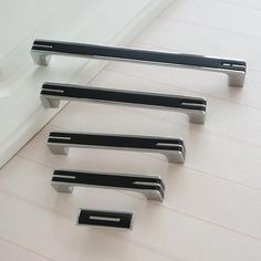 three black and silver handles on a white wall