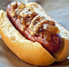 a hot dog with toppings sitting on top of a bun