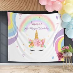 a unicorn themed birthday party with balloons and streamers in the background, including a large wall tapestry