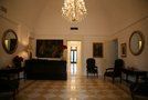 a large living room with chandelier and paintings on the walls