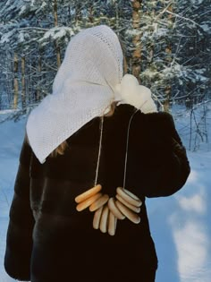 a woman wearing a white hat and black jacket in the snow with some food on her neck