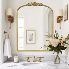 a bathroom sink with a mirror above it and flowers in a vase on the counter