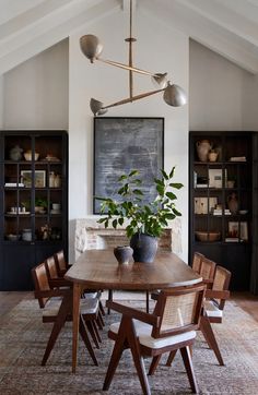 a dining room table with chairs and a potted plant