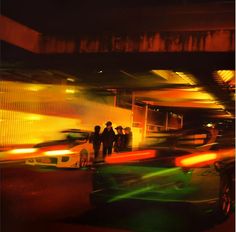 blurry photograph of people standing in front of cars