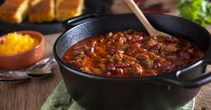 a pot filled with chili and beans next to bread