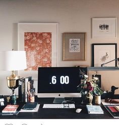 a computer monitor sitting on top of a desk next to a lamp and pictures above it