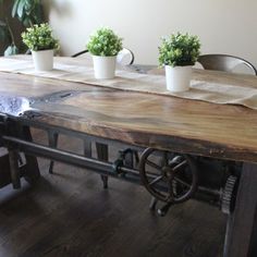 three potted plants are sitting on top of a wooden table with metal legs and wheels